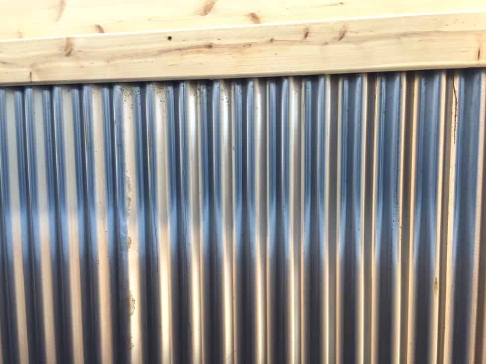 An untreated corrugated metal fence