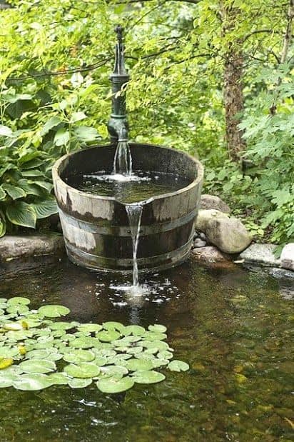 A backyard water feature that includes a rustic fountain and a pond