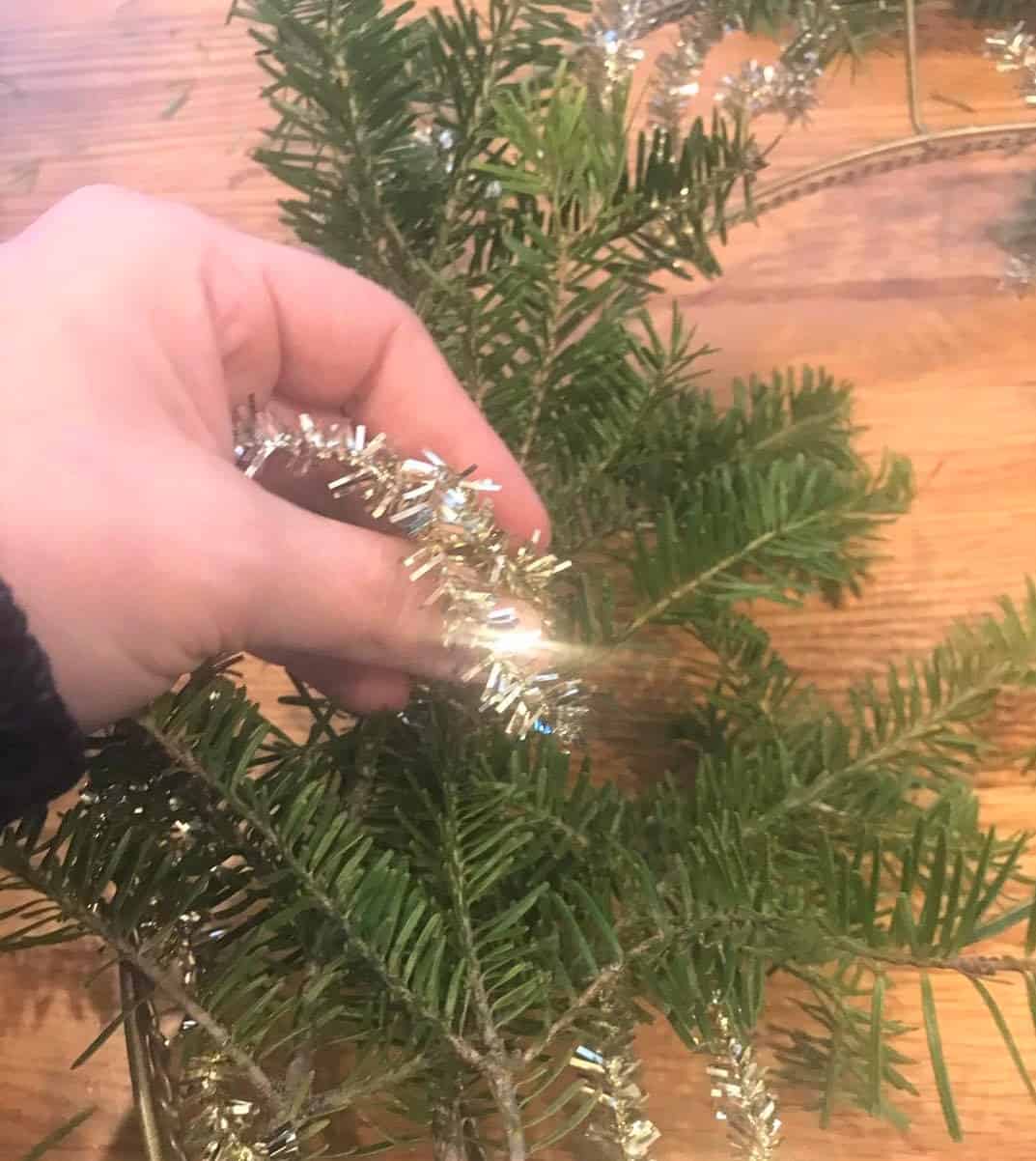 an evergreen Christmas holiday wreath is decorated with tinsel