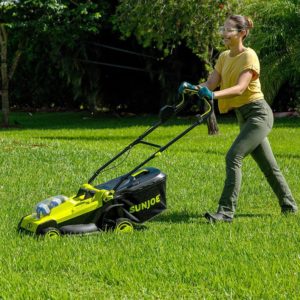 Woman using Sunjoe cordless electric lawn mower