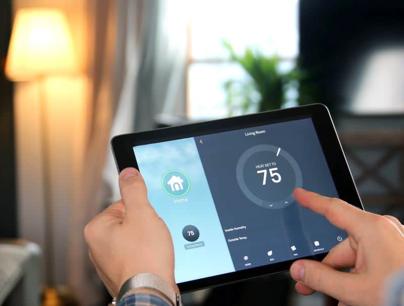 a man adjusts a smart thermostat using his tablet computer