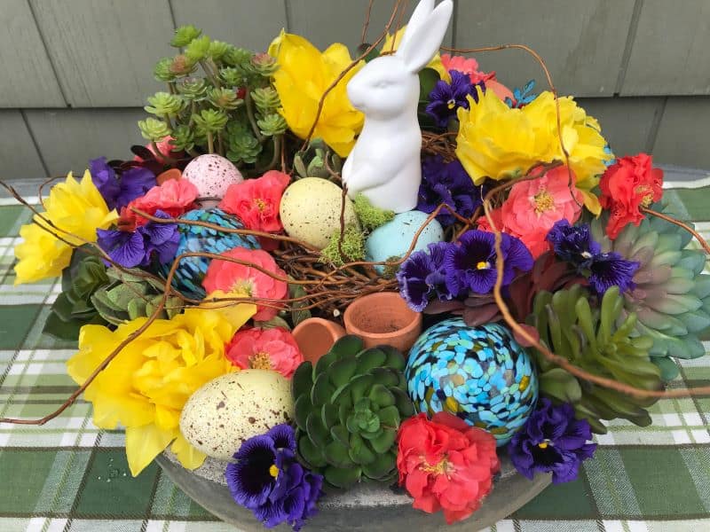 An Easter-themed flower arrangement that features freshly picked garden flowers, succulent foliage and a bunny figurine.