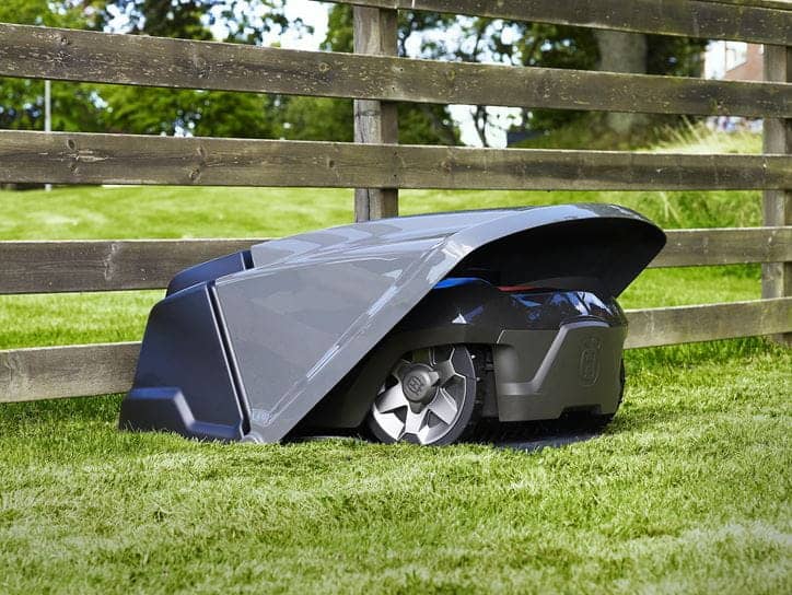 a robotic lawn mower sits under its charging station cover
