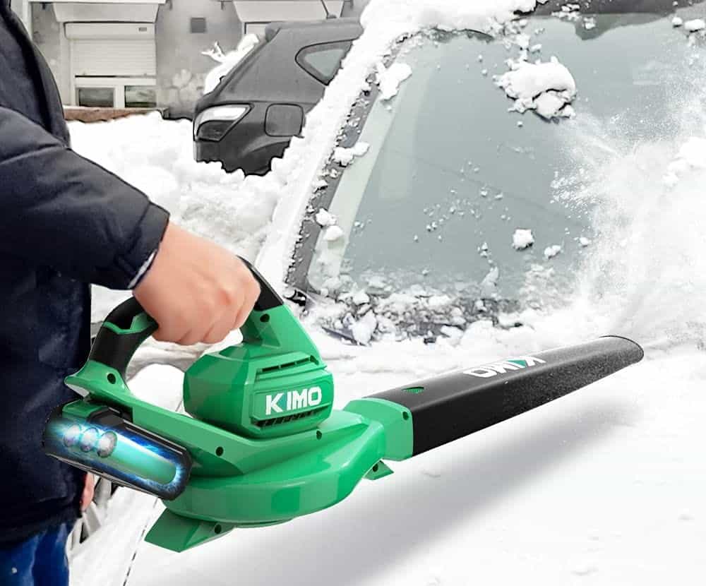 man uses a Kimo leaf blower to blow snow from car windshield