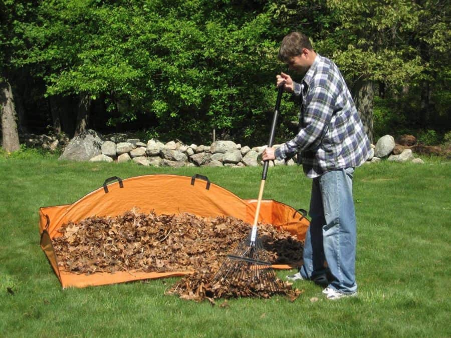 a man rakes leaves into an EZ Leaf Hauler leaf gathering tool