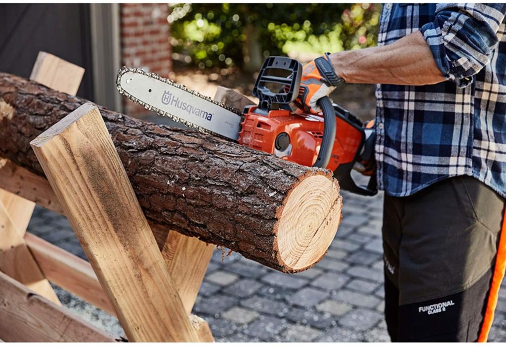 a man cuts a log using a battery powered chainsaw