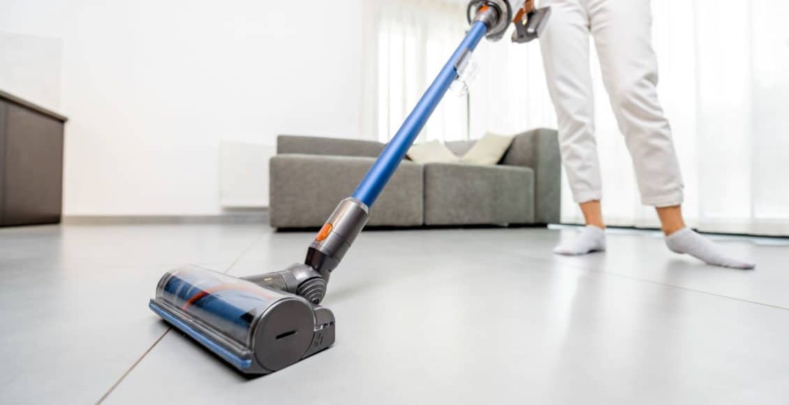 woman vacuuming floor with a cordless vacuum cleaner