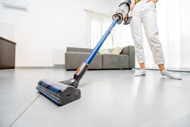 woman vacuuming floor with a cordless vacuum cleaner