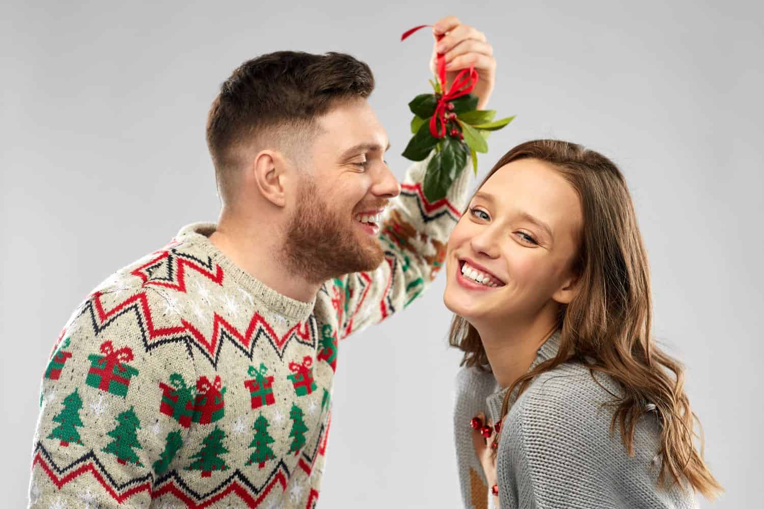 a young couple kiss under mistletoe