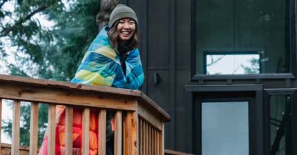 a woman is wrapped in a colorful blanket to keep warm outdoors