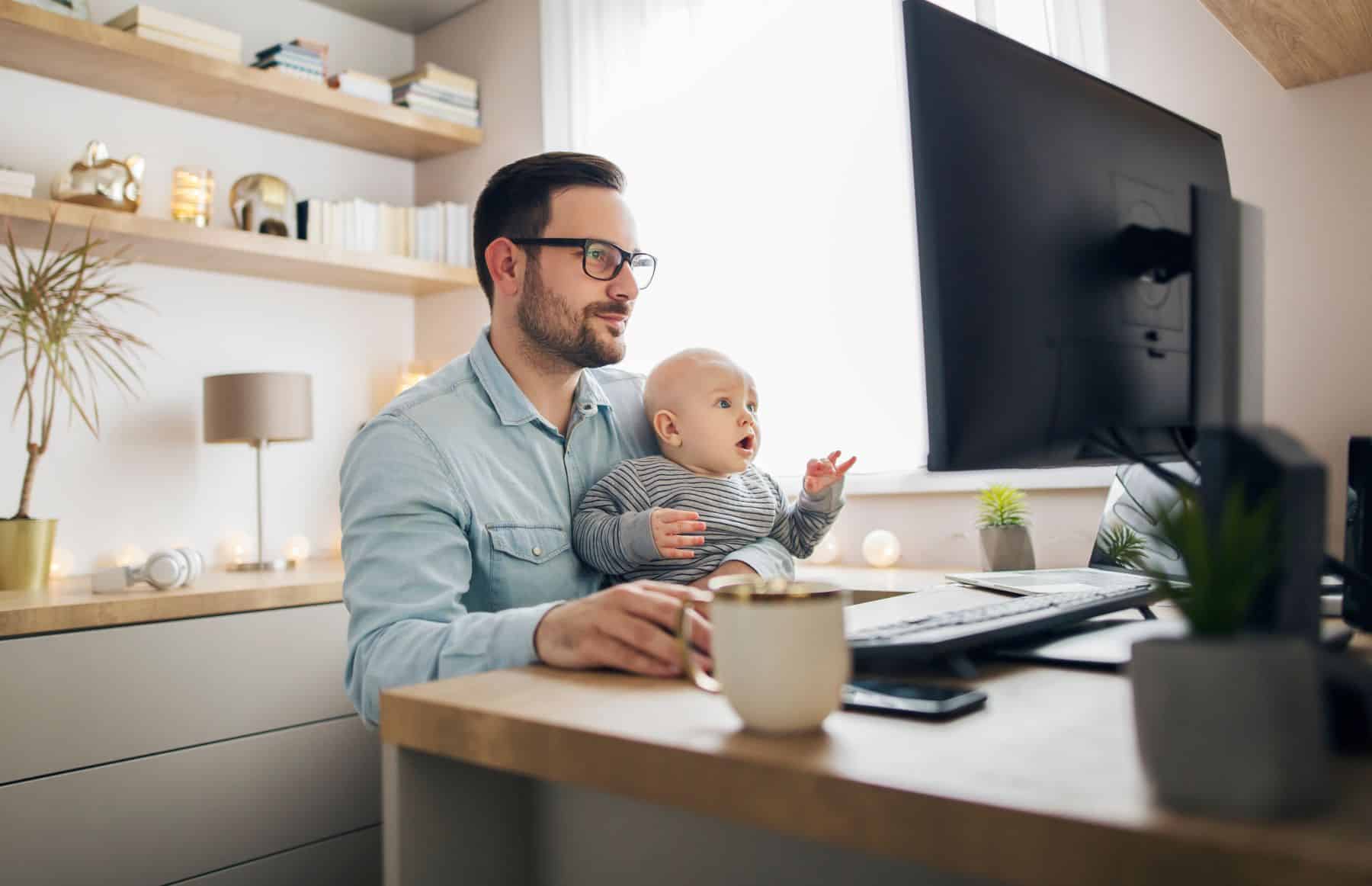 man in home office with baby on his lap