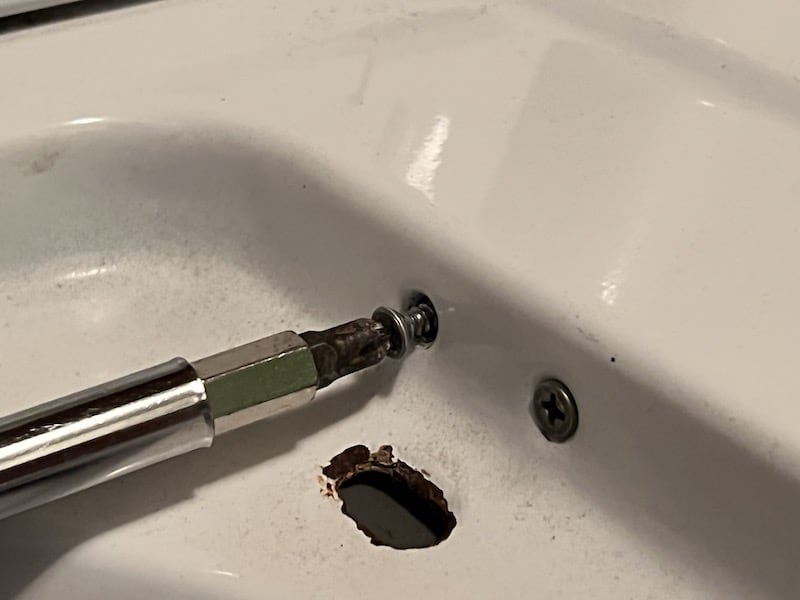a screwdriver removes a screw during an easy DIY washer repair