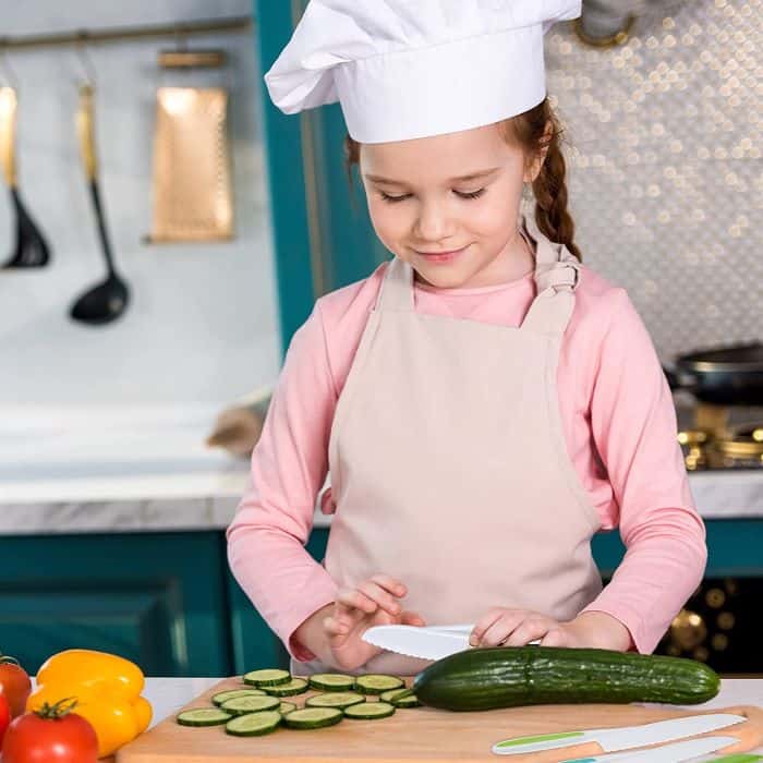 a girl safely cuts a cucumber in the kitchen with safety knives