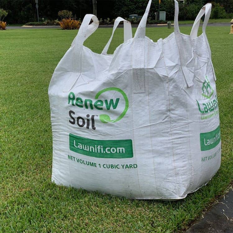 a bag of renew soil sitting on a lawn