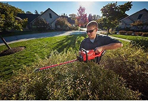 a man uses a milwaukee cordless electric hedge trimmer