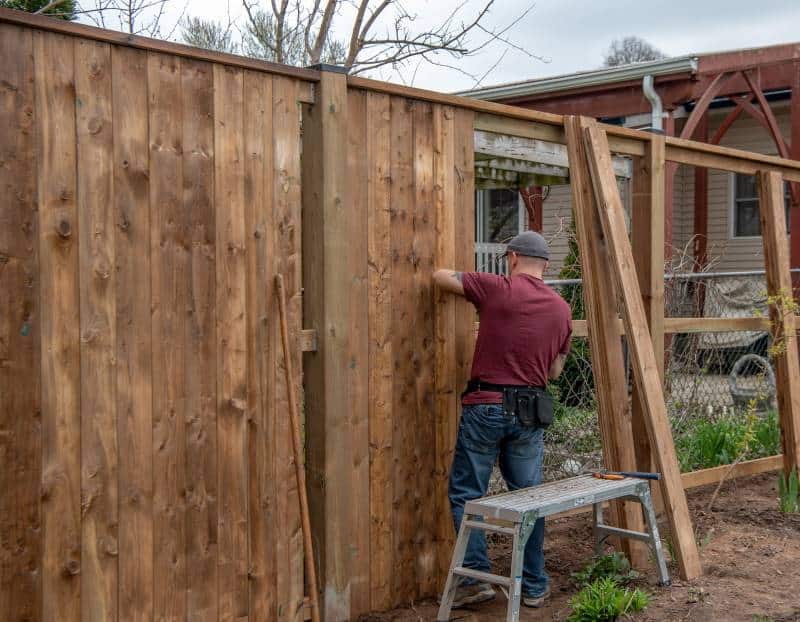 install a garden fence: a man builds a fence in his yard