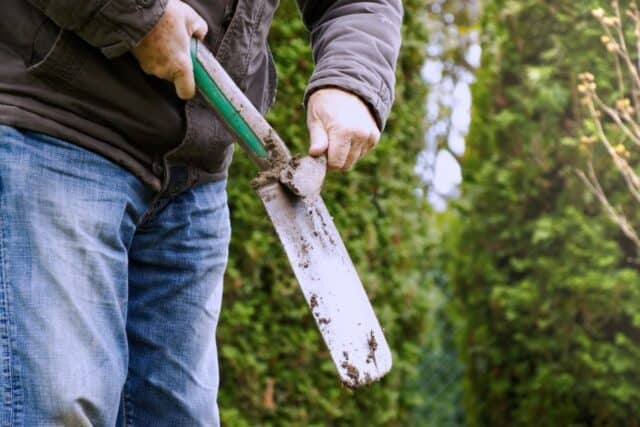 cleaning the dirt off a garden shovel spade